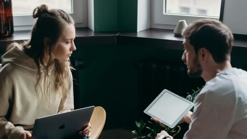 ノートPCとタブレットを使って会話する男女